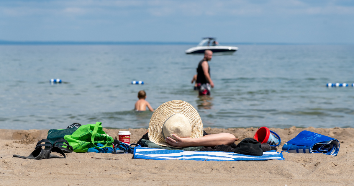 woman lying on beach with boat in background Georgina Ontario