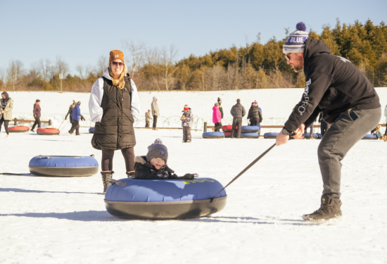 parent pulling child in a snow tube
