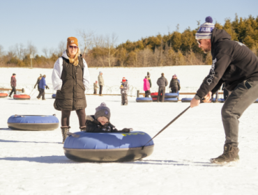 parent pulling child in a snow tube